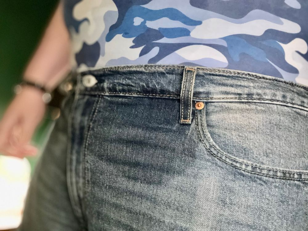 A chubby man wearing a pair of jeans with a large wet patch on the front