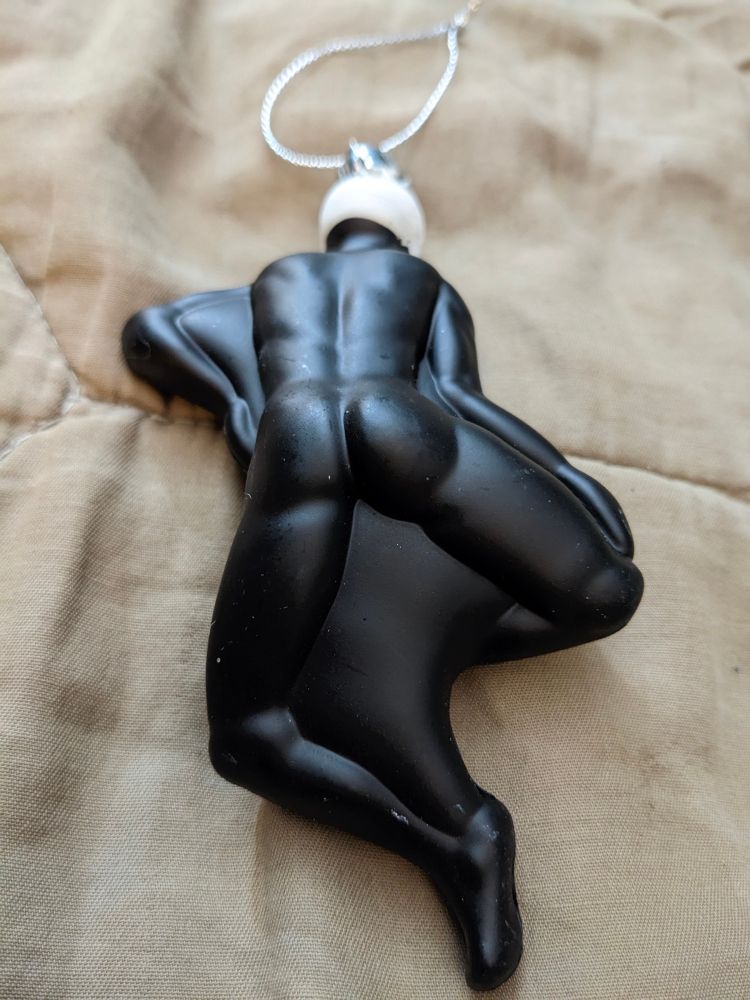 The backside of the skeleton ornament, which is completely black with no painted bones aside from his skull, and he is CAKED UP. His pose looks very suggestive while laid face down.