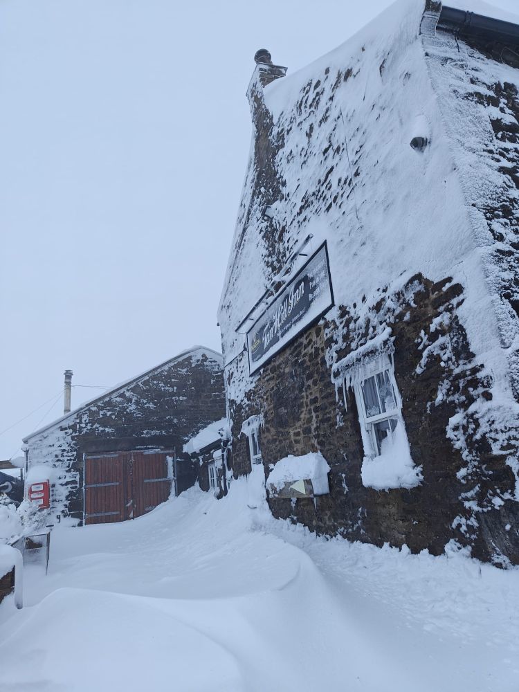 A snow drift up to some of the windows of the Tan Hill Inn