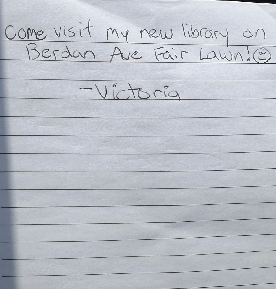 A handwritten note on lined paper that reads “Come visit my new library on Berdan Ave Fair Lawn! ￼￼￼￼￼-Victoria”