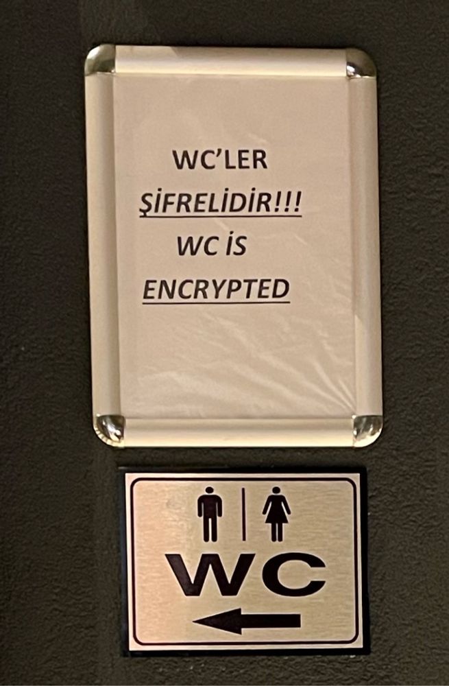 WC sign and a printout next to it saying “WC İS ENCRYPTED” in both English and Turkish