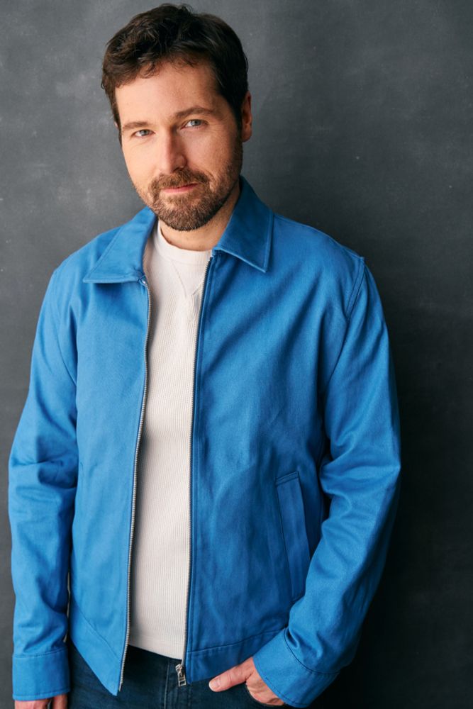 Kyle in a white shirt with a blue suede jacket