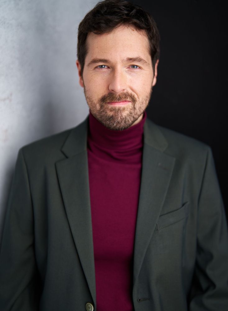 Kyle in a maroon turtleneck with a olive green blazer