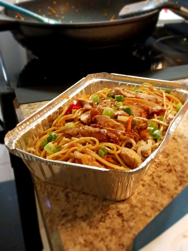 The lo mein dish packed in a foil plate so it can be delivered to its recipient, my mom.