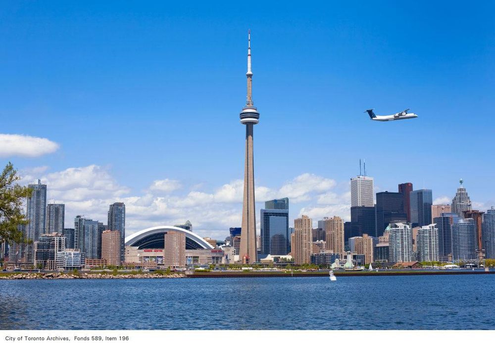 The Toronto skyline seen across the water from Hanlan's Point on a clear day in 2009. A small plane is taking off from the Island Airport into a bright blue sky. Photo by Peter Mintz, Fonds 589, Item 196.