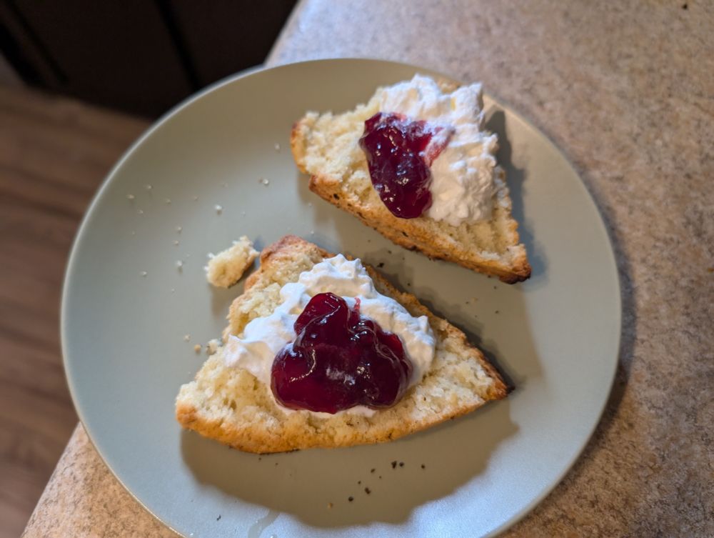 Scone, split in half, with whipped cream and raspberry jam on each half