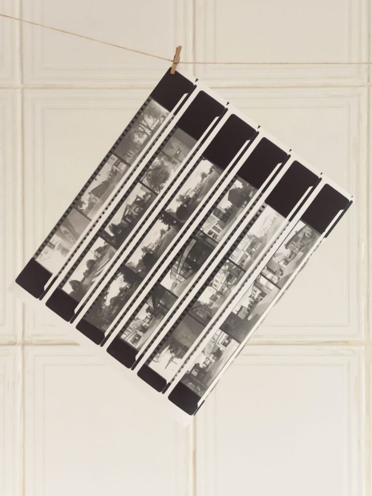 A contact sheet of black and white negatives hanging to dry