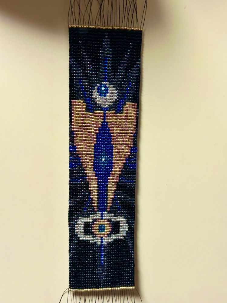 ビーズタペストリー。サイバトロン星、センチネルの翼、マトリクスがモチーフとして描かれている。