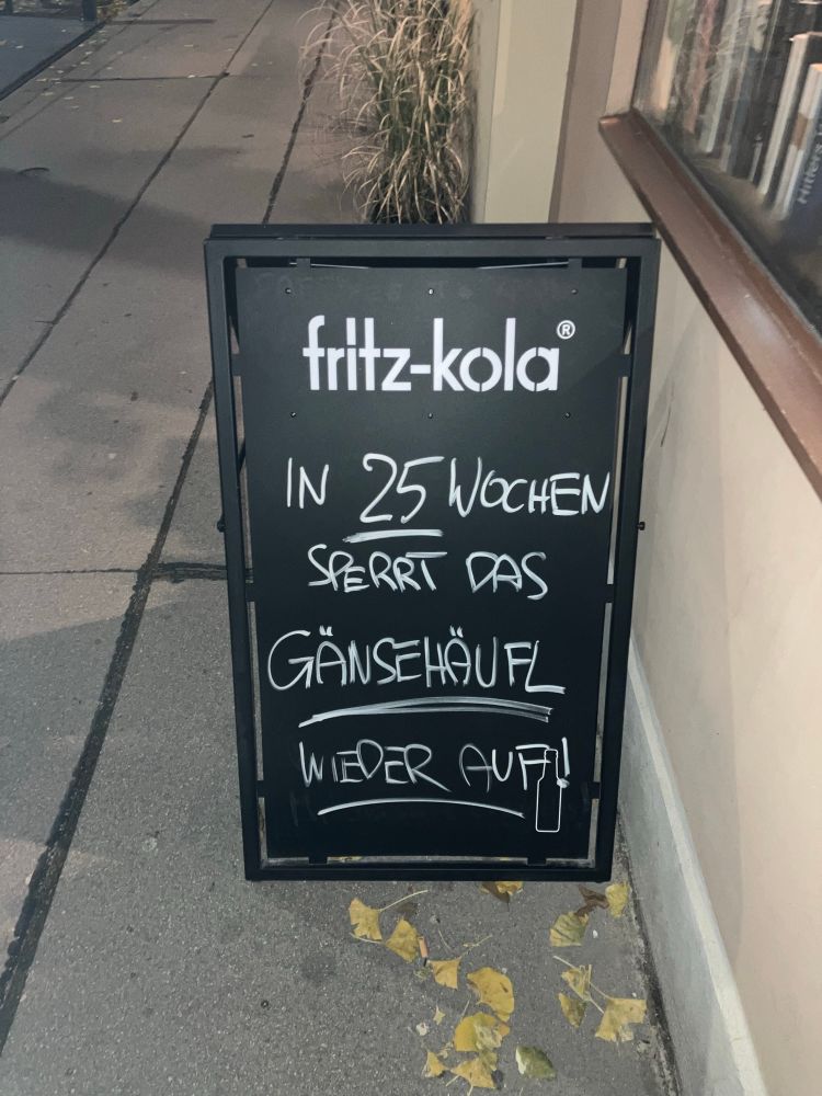 Stehtafel vor einem Lokal in Wien, weiße Kreide auf schwarzem Grund: „In 25 Wochen sperrt das Gänsehäufl wieder auf!“ 