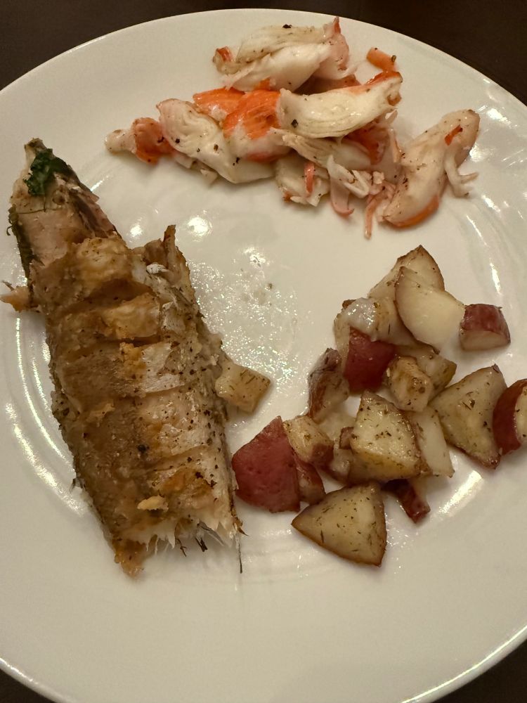 A plate of food: fried fish, potatoes cooked with spices and rosemary, and imitation crab