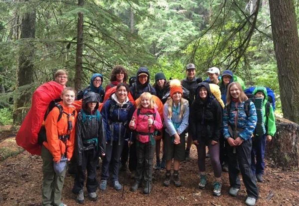 A group of girls and boys, ages 11-17, stand in a temperate rainforest equipped for a backpacking trip. It's a bit rainy and their colorful raingear contrasts with the rich green of the trees in the background.
A group of girls and boys, ages 11-17, stand in a temperate rainforest equipped for a backpacking trip. It's a bit rainy and their colorful raingear contrasts with the rich green of the trees in the background.