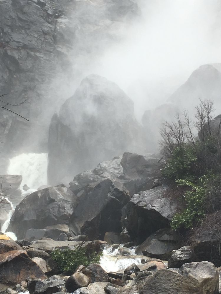 Mist falling over large, jagged rocks at the bottom of a spring waterfall. Photograph from Yosemite National Park.