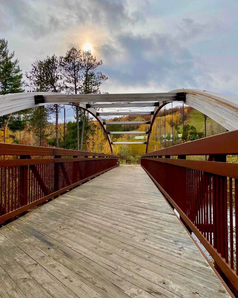 An arched wood and steel bridge spans a river in Northern Minnesota. 