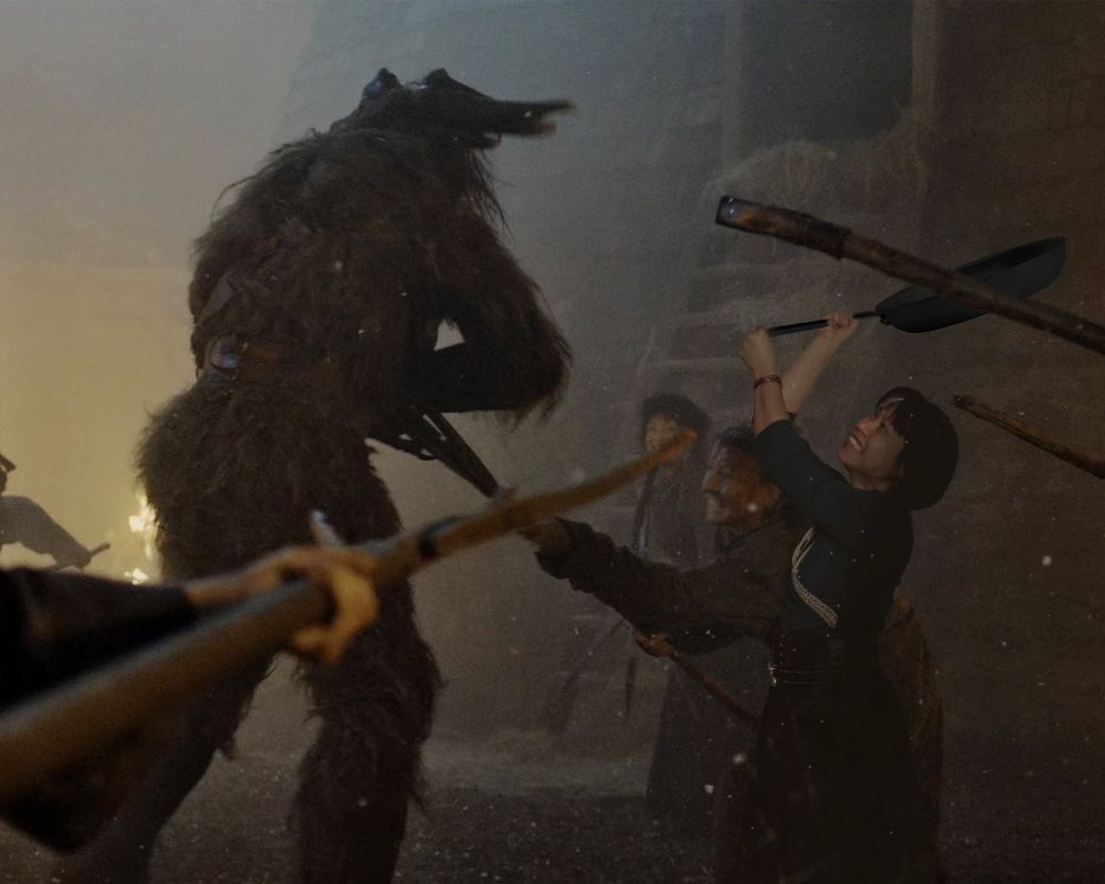 Myself dressed in the Two Rivers costume holding a large frying pan over my head about to hit a Trolloc towering over a few more Women Circles.