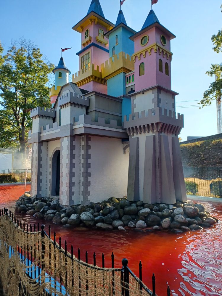 Tiny pastel pink & blue castle surrounded by red-colored water.