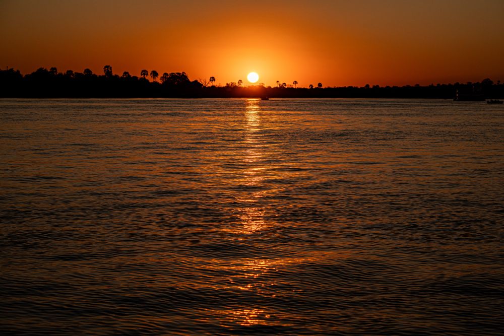A deep orange sunset over a wide river, taken on the water
