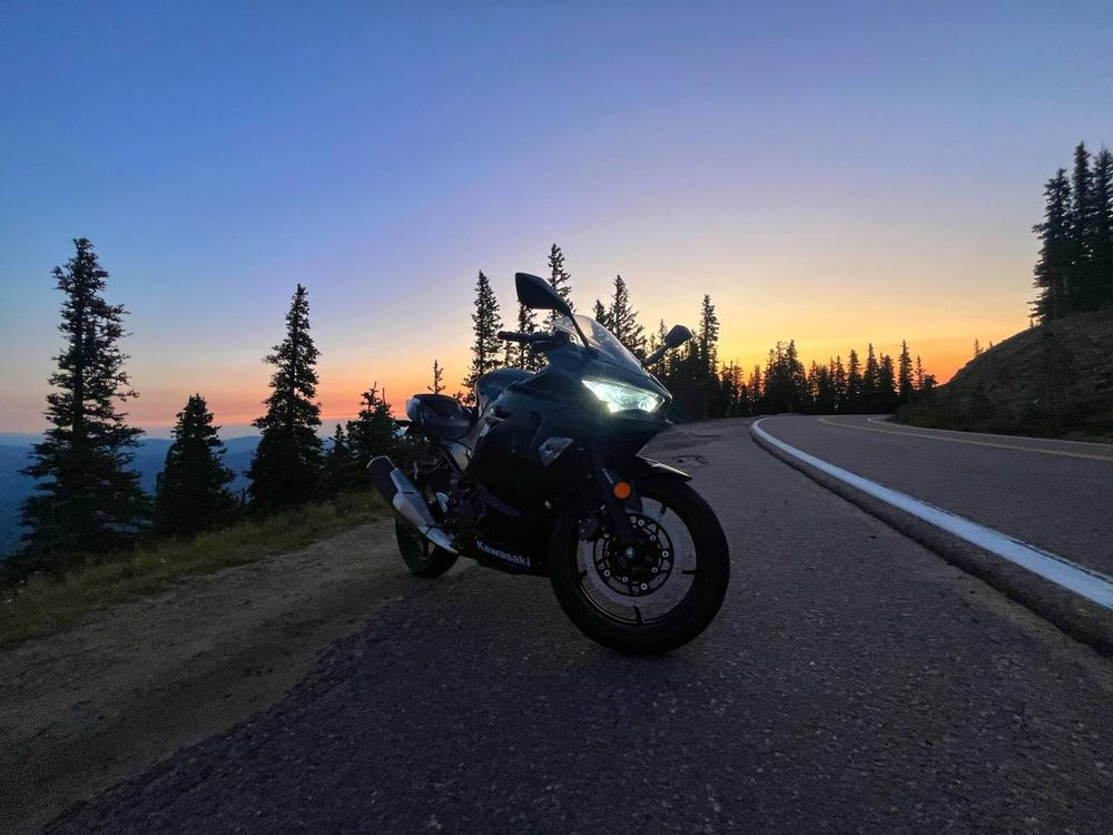 Black Kawasaki ninja on the shoulder of a curved highway at high elevation at sunrise
