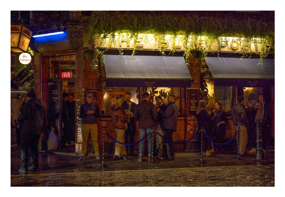People drinking outside the Blue Posts in Soho at night
