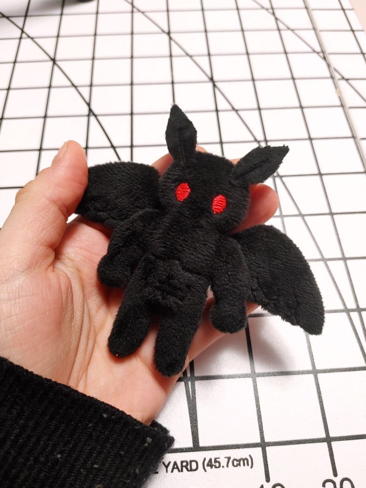 A palm-sized plushie of a very muscular mothman
