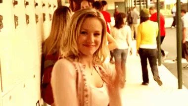 a woman is standing in front of a row of lockers in a crowded hallway .