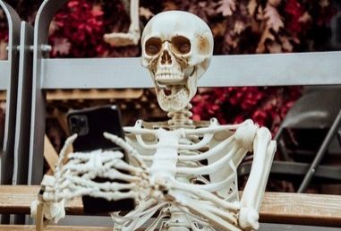 Um esqueleto com um celular nas mãos. Ele está com a boca aberta.