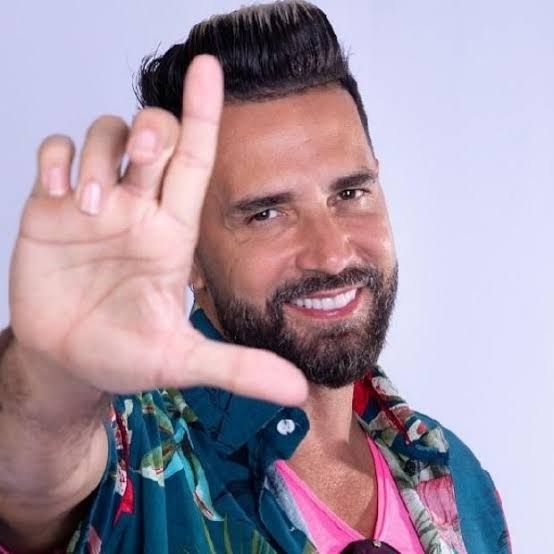 O cantor Latino fazendo o L com os dedos da mão. 