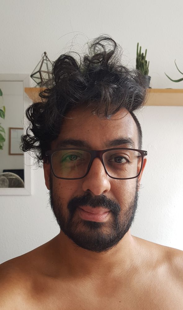 Selfie minha. Homem negro usando óculos e com um cabelo que lembra um ninho de passarinho bagunçado na cabeça. 
