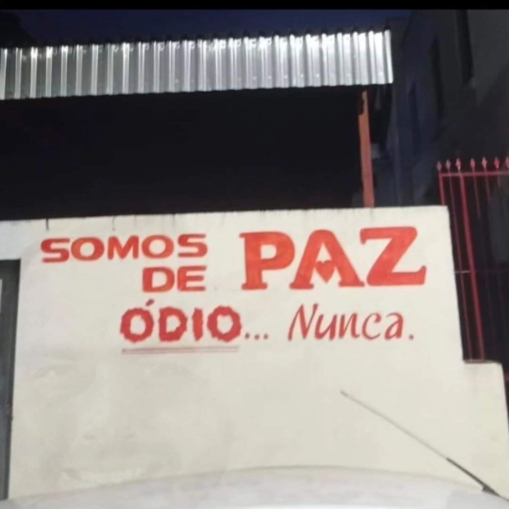 Muro branco com o texto Somos de Ódio... Paz Nunca escrito em letras vermelhas. 
