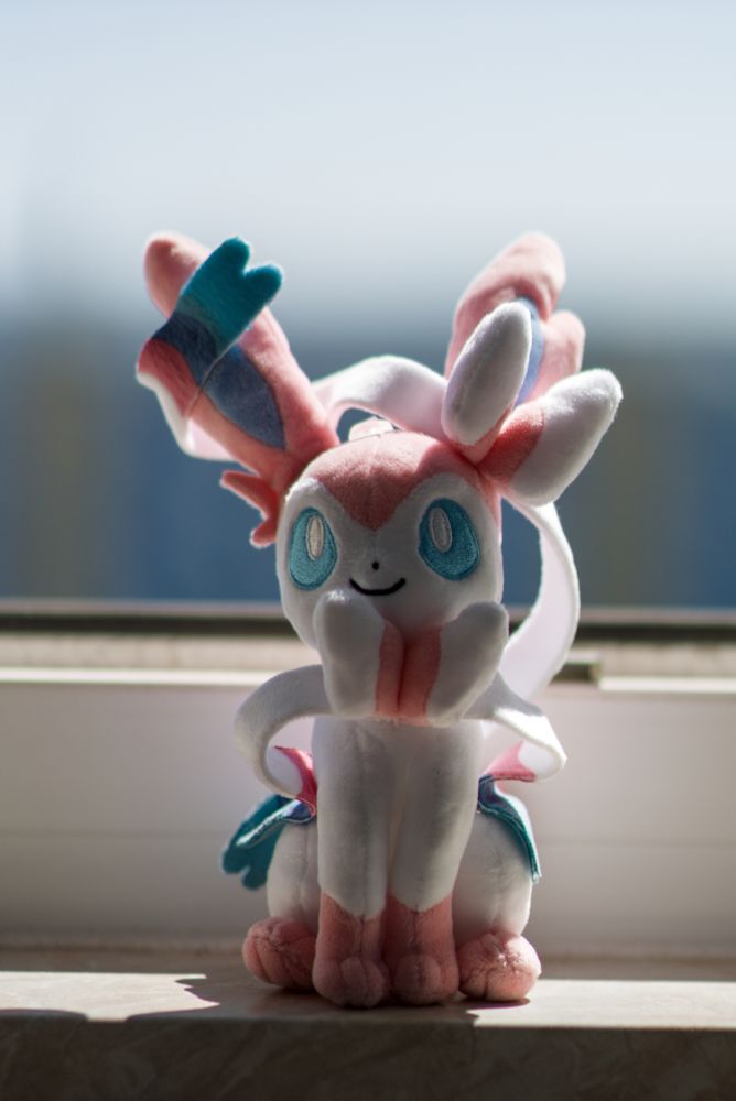 Sylveon pokemon plushy with very blurry background