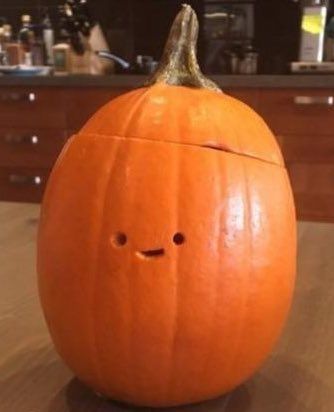a tall jack-o-lantern with a tiny, crudely cut smiley face in the center of the pumpkin