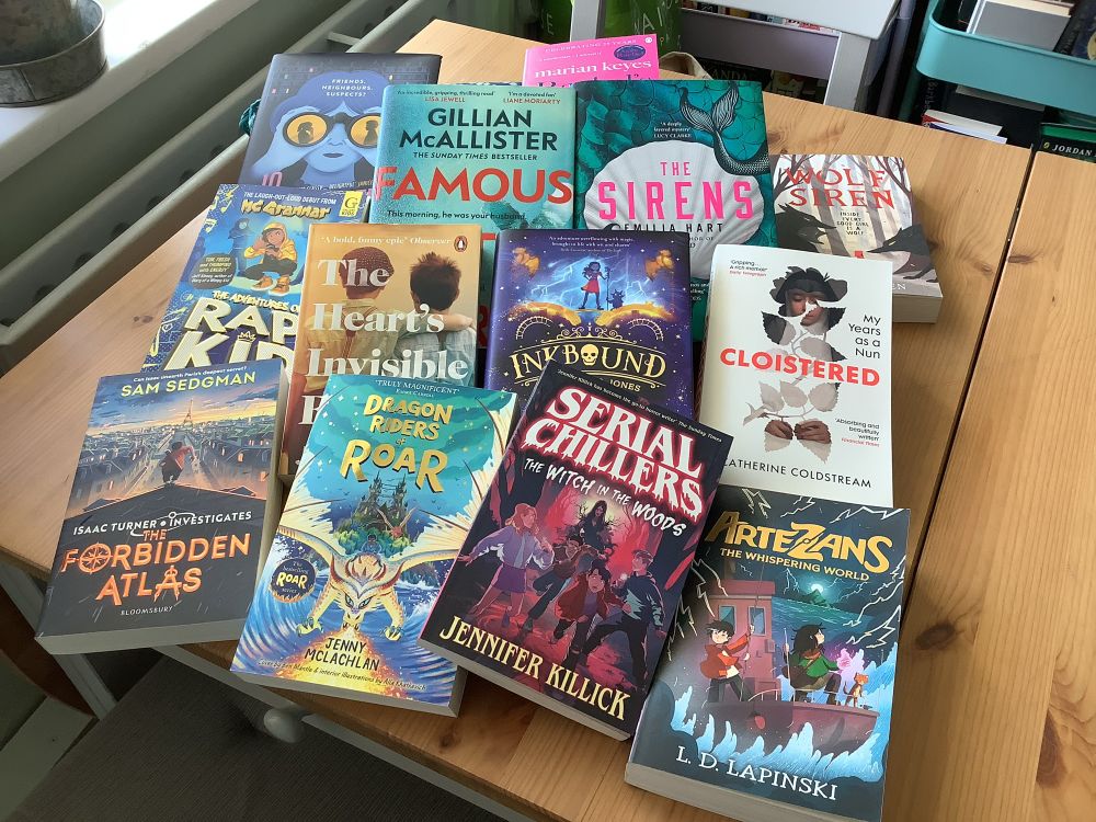 A table top full of books! 13 of them to be precise. A selection of children’s and adults including Serial Killers by Jennifer Killick, Artezans by LD Lapinski, The Sirens by Emilia Hart. 
