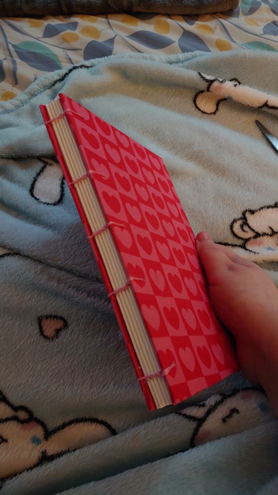 A pink thread bound book with a red and pink heart checkered fabric cover