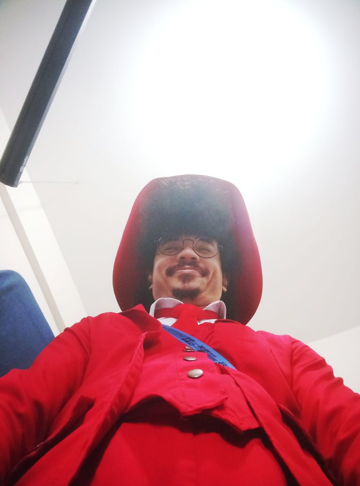 Foto de Rik tirada de baixo pra cima
Ele está com roupa vermelha e uma cara plena