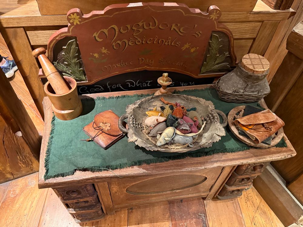 Cabinet with sign, mortar and pestle, dish of crochet mice, leather pouches, and other containers. 