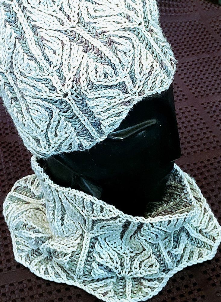 Two colour brioche knit hat and cowl on a black, stylized hat form, sitting on top of a black background