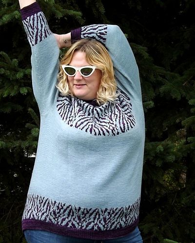 Sam is wearing animal pattern yoke and cuffs sweater, MC Natural Ewe (indigo) and CC ArtFil Belle eggplant colour. She shows off in white sunglasses.