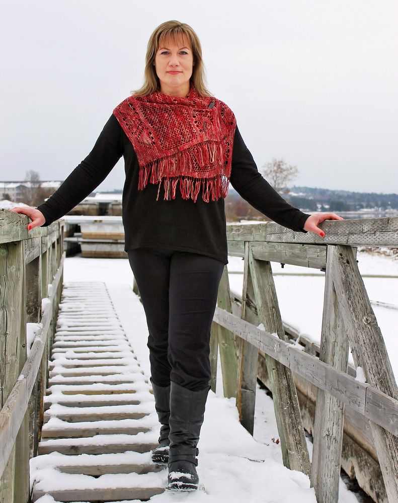 Lady walks down gangway, wearing a smaller red shawl fastened in front.