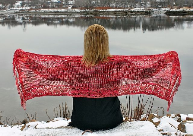 Lady sits on riverbank, spreading her red shawl out in a wingspan pose. 