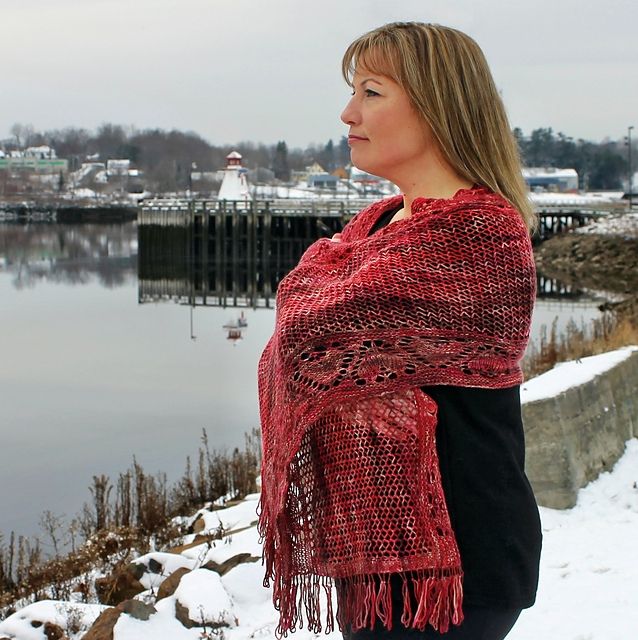 Lady stands on riverbank, wrapped in her red shawl.