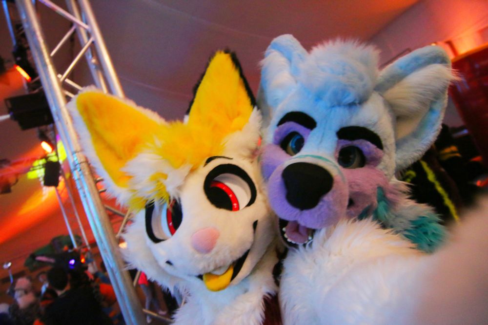 Fons the Bun and Keenora are hugging each other, Keenora behind Fons, taking a selfie, both in their fursuits.