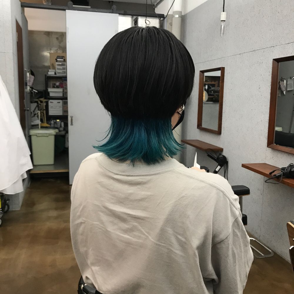 後ろ姿の人。ウルフヘアで襟足が青緑