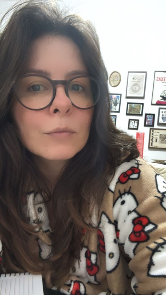 mulher branca, usa óculos de grau e um roupão felpudo da personagem hello kitty 