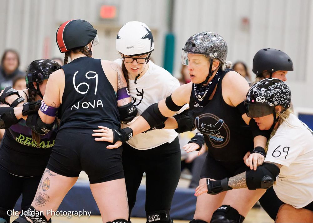 Blockers and jammers in roller derby. One of the black blockers appears to have a hand on another blocker’s buttcheek. lol