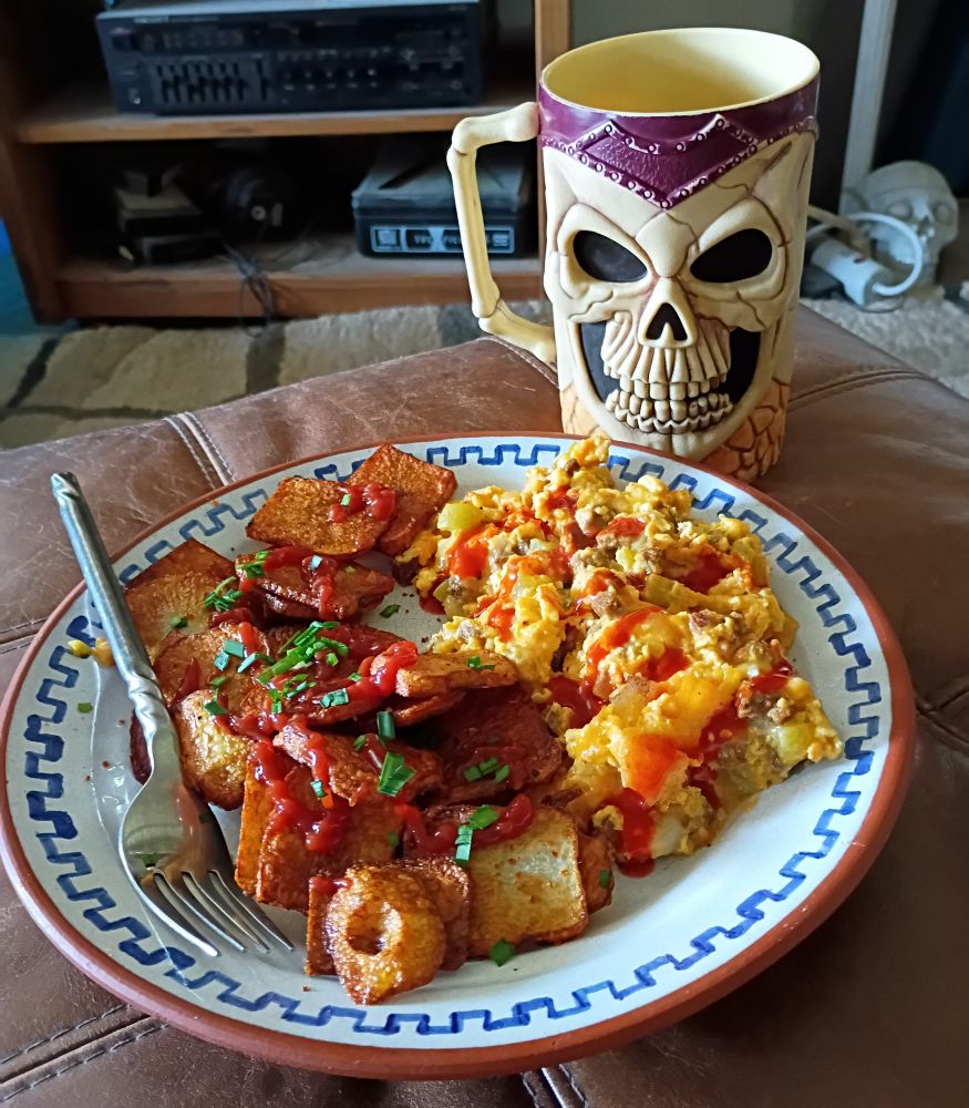 A Mexican-style plate with with eggs scrambled with chorizo, cheese, and green chilies, topped with salsa picante, and a side of home-fried potatoes with catsup and home-grown chives. 