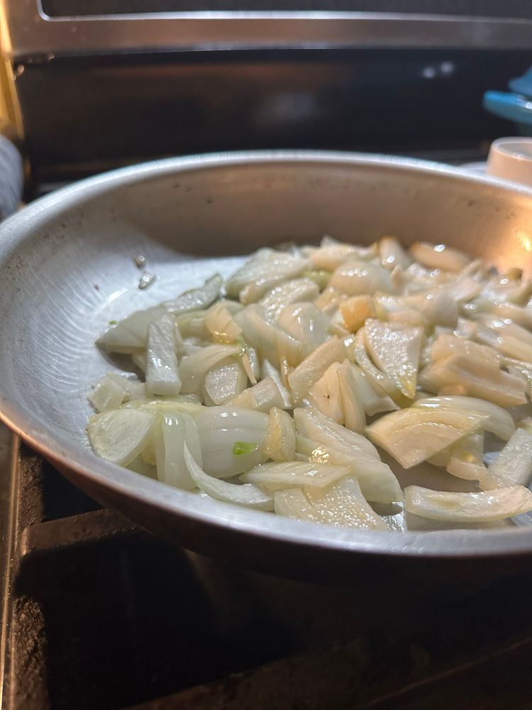 A photo of cut up onions in a frying pan