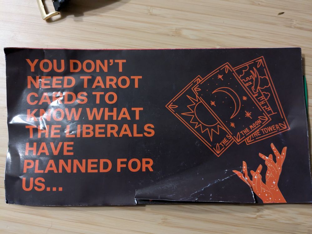 Ominous orange text, all caps, on a black background, reading:

"You don't need Tarot cards to know what the Liberals have planned for us..."

To the right of the text is a line drawing in the same colour of three Tarot cards - the Sun, the Moon and the Tower - above a pair of star-spangled hands gesturing mysteriously.