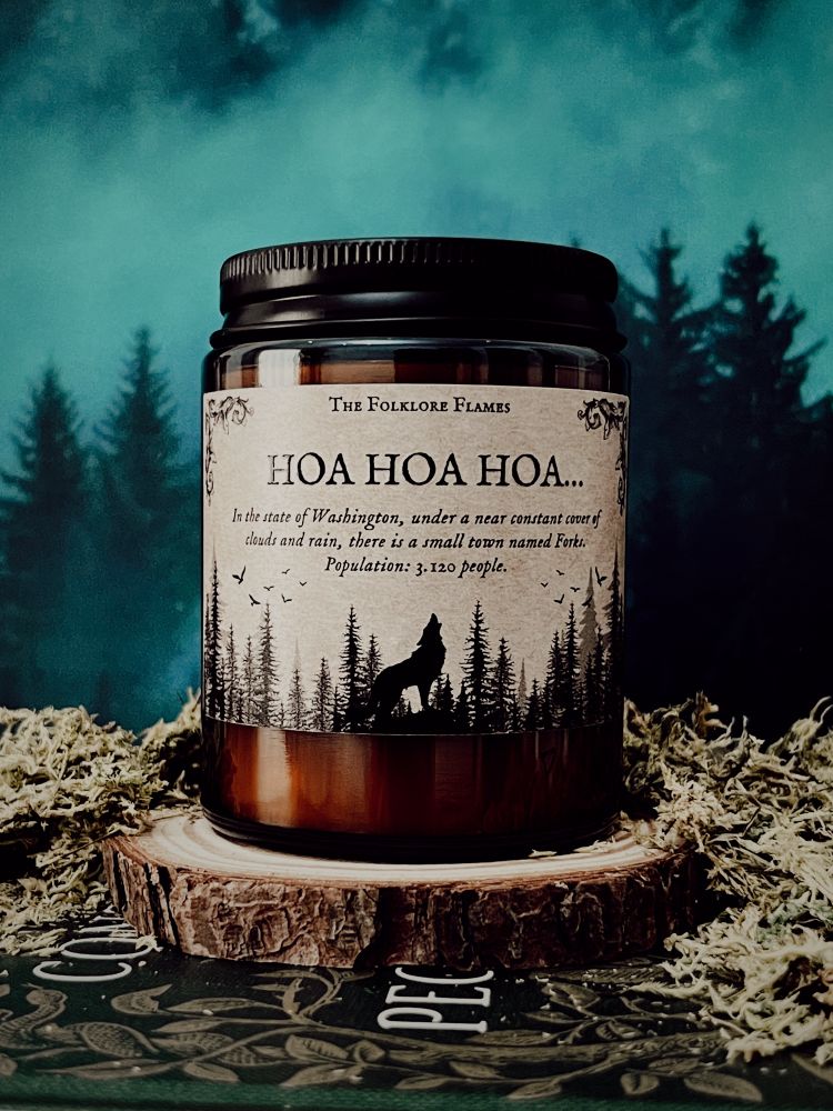 A foto mostra uma vela inspirada no filme/livro Crepúsculo, o nome da vela “Hoa Hoa Hoa” é um trocadilho com a música Eyes on Fire. A arte da vela é de uma floresta e um lobo uivando. Ela possui um fundo kraft, com ar mais “vintage”. 
