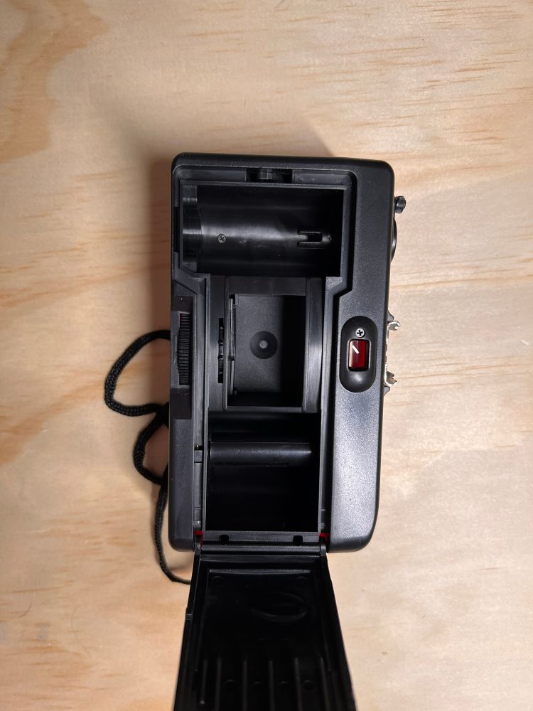 Back view of unmarked cheap plastic point and shoot rangefinder camera, with the back open showing the film reels 