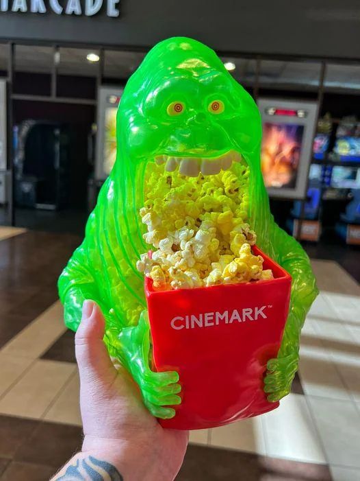 a ghostbusters: frozen empire molded plastic promotional popcorn bucket shaped like Slimer that pretty much just looks like he's hurling up popcorn into a smaller popcorn bucket