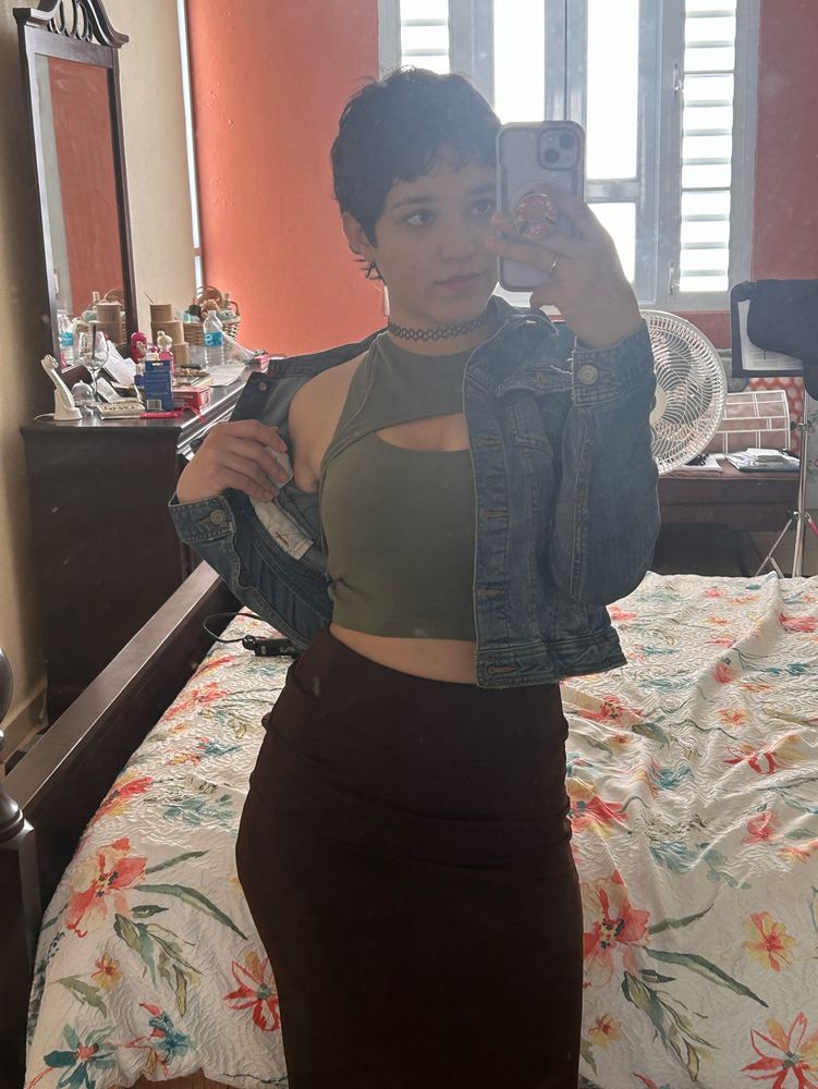 Cute pose. The jean jacket is being pulled down slightly down the shoulder by my hand while eyes stare straight into camera. Green shirt with a bit of belly shown. A brown skirt though the picture stops at knee length.